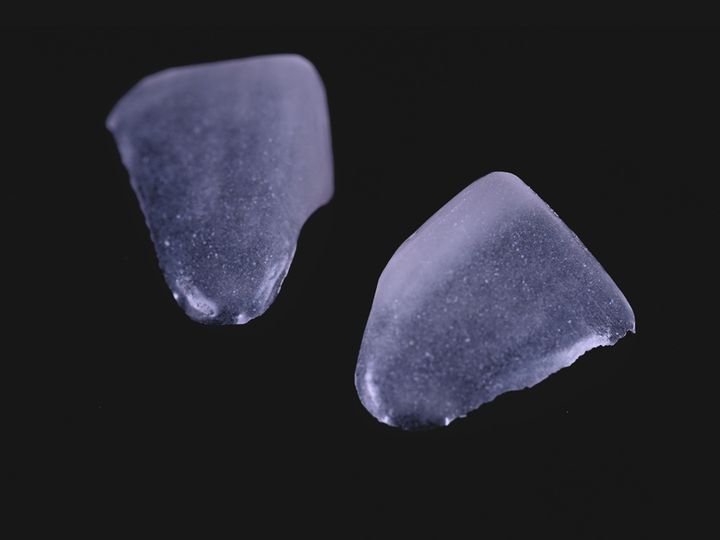 Two translucent feldspathic veneers on a black background